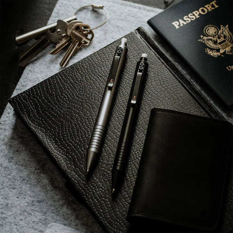 A sleek 0.5 mechanical pencil surrounded by a durable wallet, versatile multitool, sophisticated keychain, and a passport on a minimalist desk.