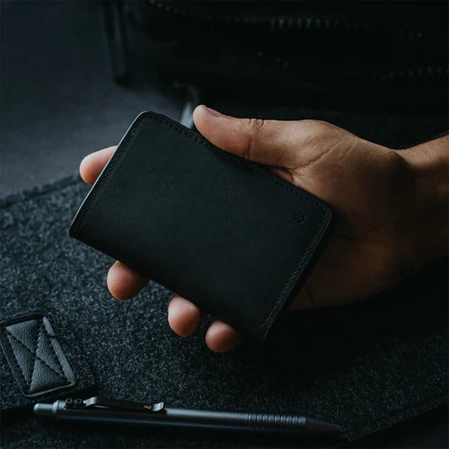 A flat lay featuring a black leather wallet and a sleek black, Grafton pen.