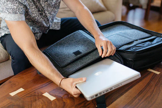 A stylish and durable men's work backpack showcased with everyday carry essentials against a wooden table.