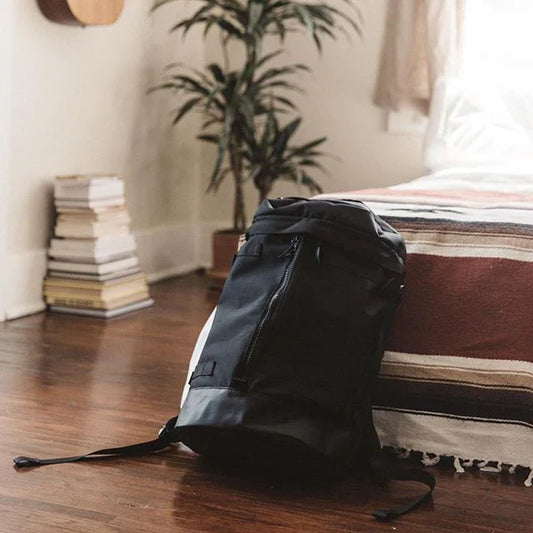 A minimalist scene featuring a sleek carry-on luggage set against a wood floor and bed in a bedroom.