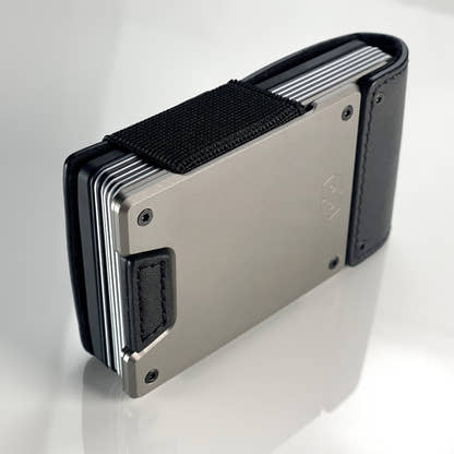 Side view of a satin gunmetal PROOF wallet with black leather straps packed with cards under its elastic band; the AirTag holder itself is not visible in this frame