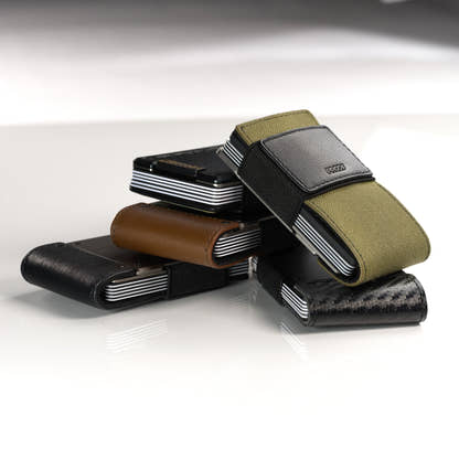 A stacked group of PROOF wallets in olive nylon, brown leather, black leather and carbon fiber; the AirTag holder itself is not shown in this frame
