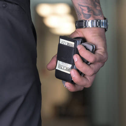Hand holding the PROOF Apex wallet with cash folded under the exterior elastic strap