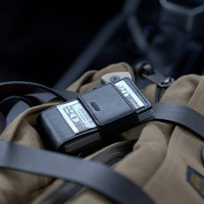 PROOF Apex wallet resting on a canvas bag with bills held under the elastic cash strap