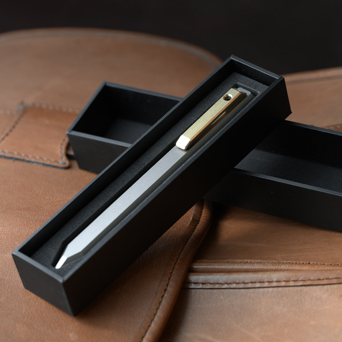 PROOF Vanguard pen seated in its open black presentation box on a brown leather surface