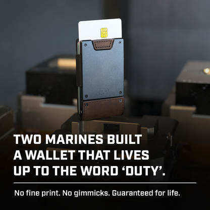 PROOF Founder wallet standing upright against blurred workshop machinery with a card fanned out, captioned 'Two Marines built a wallet that lives up to the word duty. No fine print. No gimmicks. Guaranteed for life.'