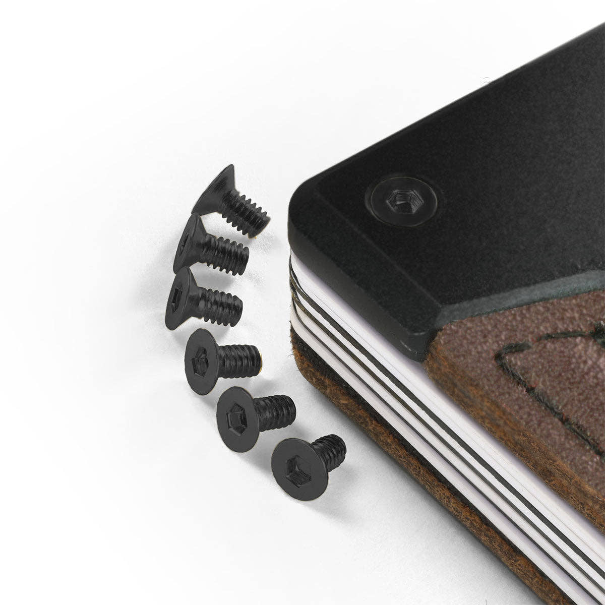 Black PROOF wallet bolts in short and long lengths beside a wallet corner fitted with a matching black bolt