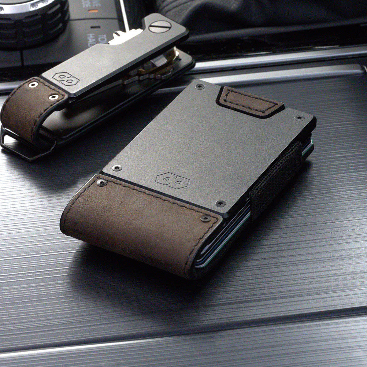 PROOF Founder wallet in bomber leather beside the matching PROOF key holder on a brushed metal surface