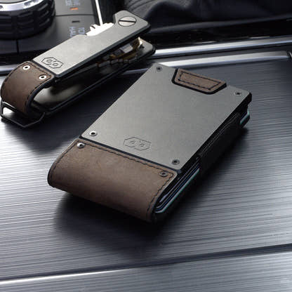PROOF Founder wallet in bomber leather beside the matching PROOF key holder on a brushed metal surface