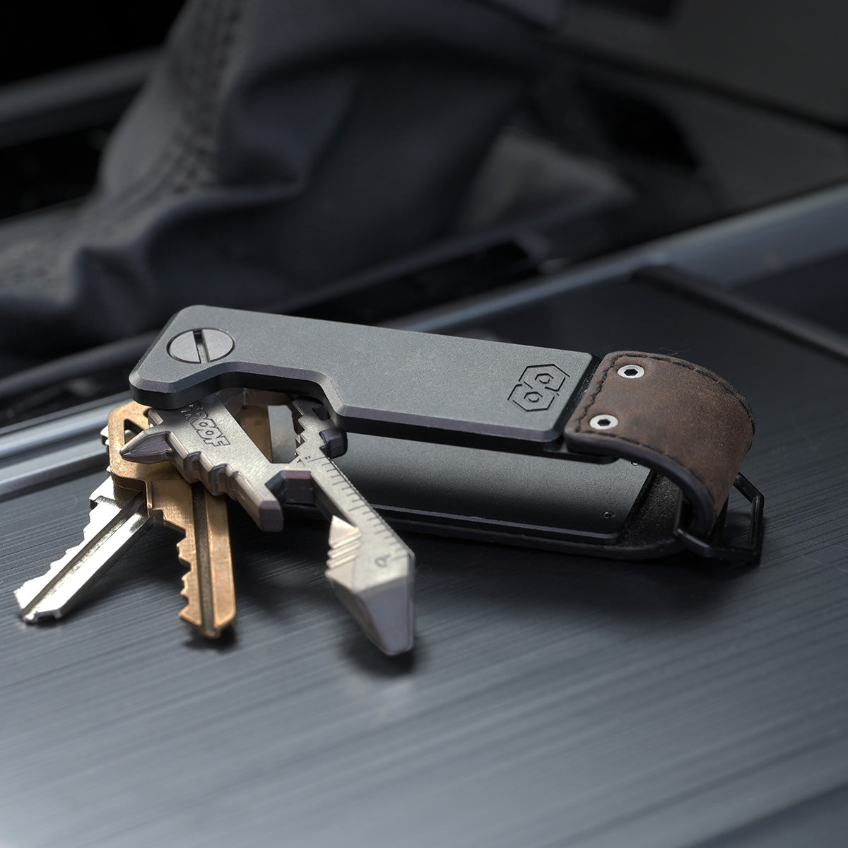 PROOF Founder key holder open on a dark textured surface with three keys and a key-shaped multi-tool fanned out