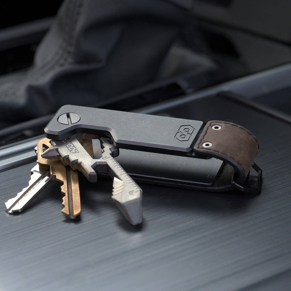 PROOF Founder key holder open on a dark textured surface with three keys and a key-shaped multi-tool fanned out