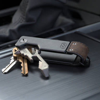 PROOF Founder key holder open on a dark textured surface with three keys and a key-shaped multi-tool fanned out