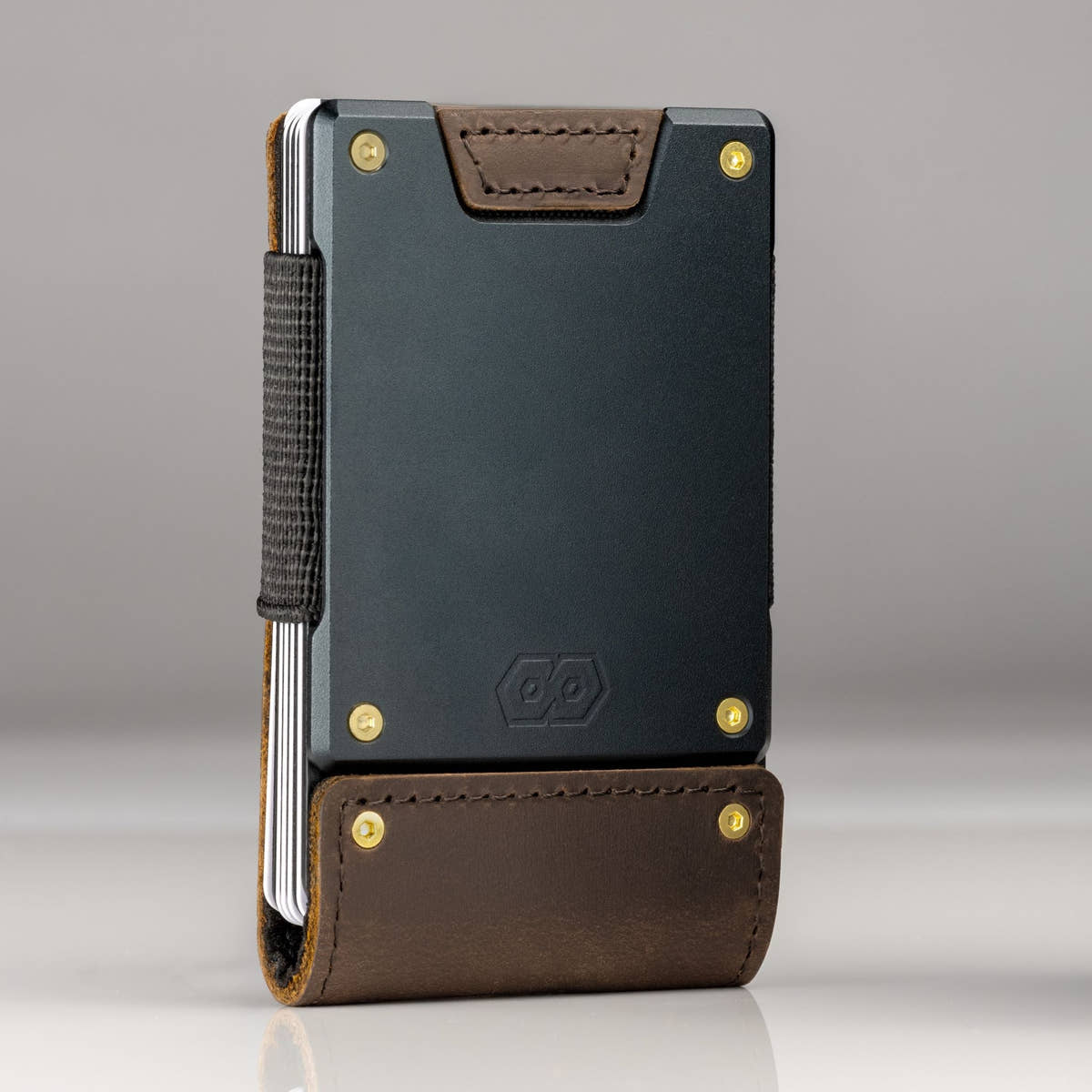 A PROOF wallet standing upright with gold bolts fitted at all four corners, showing how the hardware changes the look