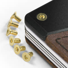 Gold PROOF wallet bolts in short and long lengths laid out beside a wallet corner with one gold bolt already fitted