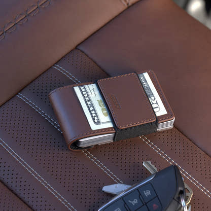 PROOF Legacy wallet on a brown perforated leather car seat with cash under its strap and a key fob alongside