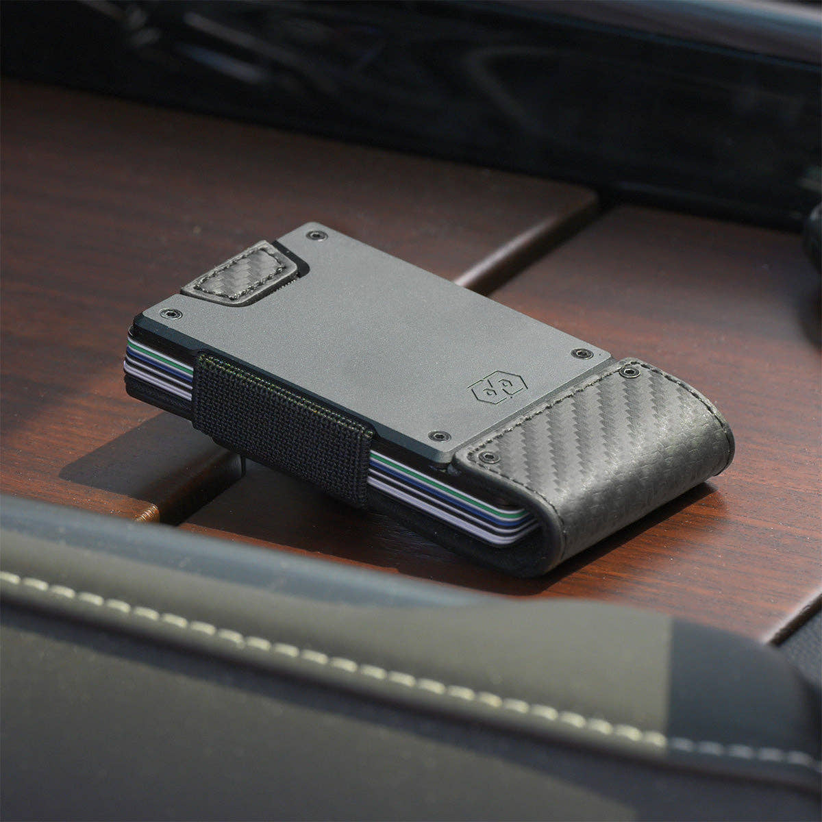 PROOF Oracle wallet resting on a wood-trimmed dashboard with cards fanned inside the aluminum frame