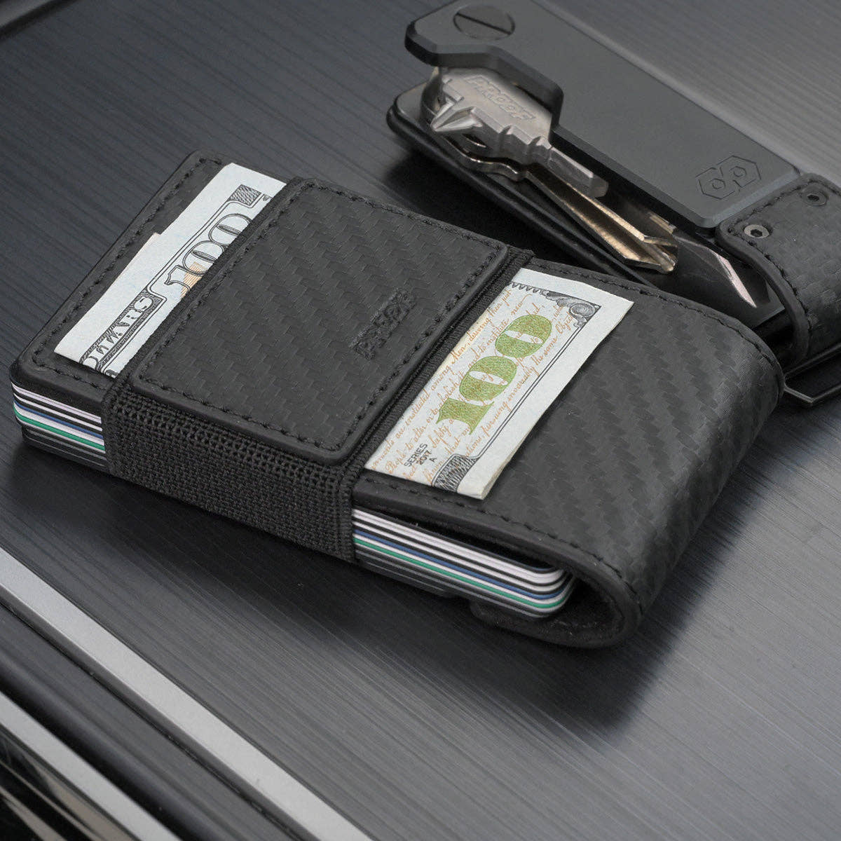 PROOF Oracle carbon fiber wallet with folded bills secured under the exterior elastic cash strap