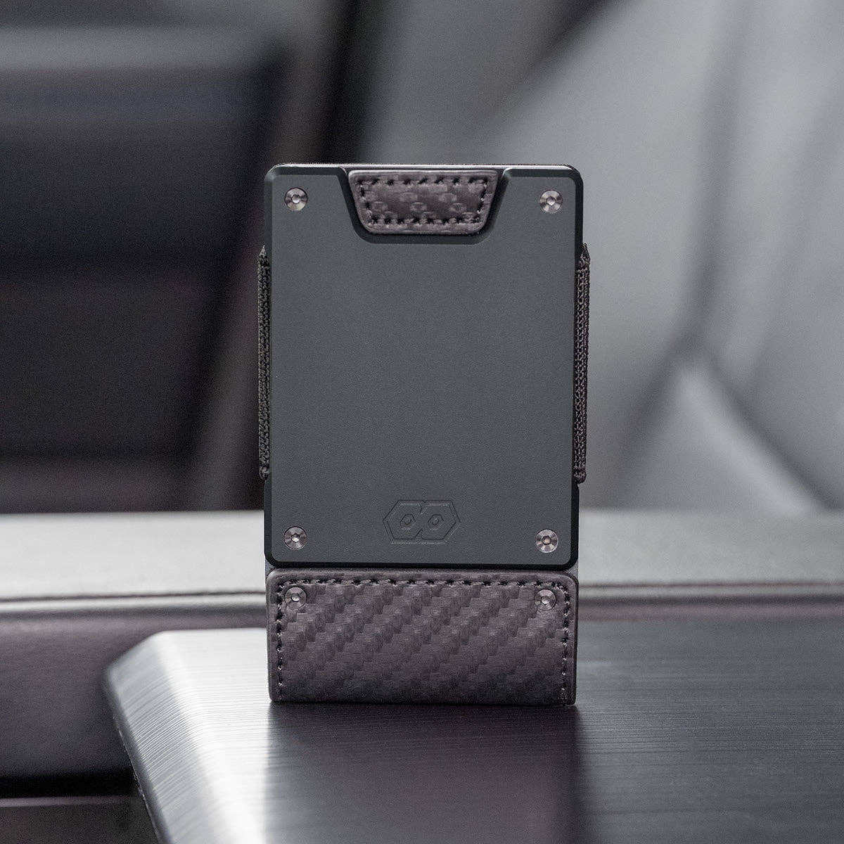 PROOF Oracle wallet standing upright on a vehicle console, showing the carbon fiber weave and embossed hexagon logo