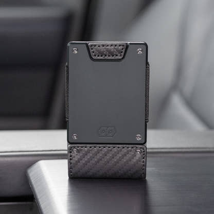PROOF Oracle wallet standing upright on a vehicle console, showing the carbon fiber weave and embossed hexagon logo
