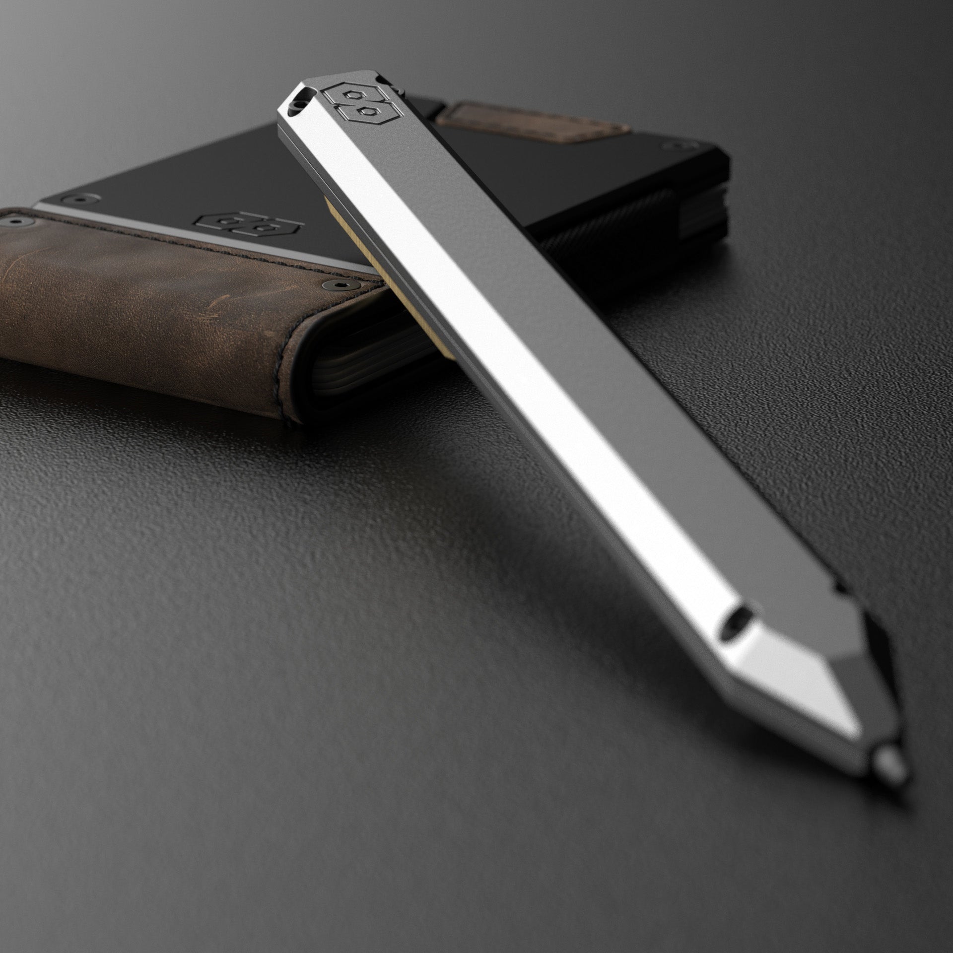 PROOF Vanguard pen propped against a PROOF wallet in brown leather, the embossed hexagon logo visible on the pen's end cap